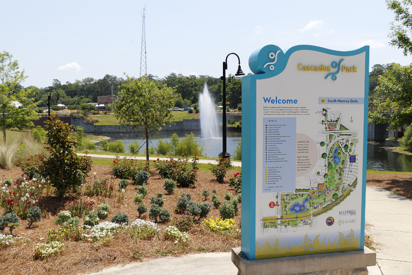 Cascades Park entrance sign and landscape. View of Cascades Park beautiful landscape with lake fountain. Sunny day at Cascades Park in Tallahassee with sign and map
