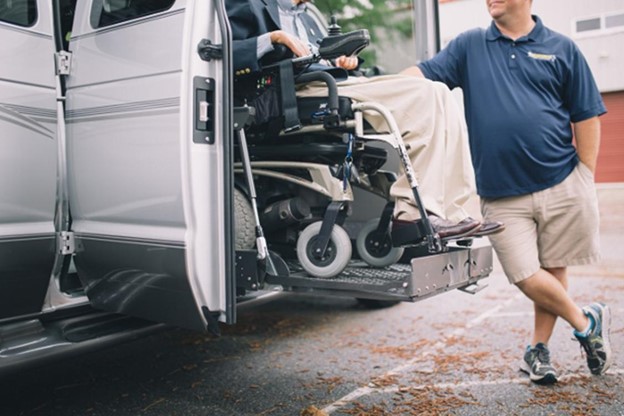 A man in a wheelchair is being assisted to get into a van, ensuring accessibility and mobility.