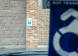 Looking through a vehicle's windshield with the handicap car tag in the background to see a handicap parking decal affixed to a brick column